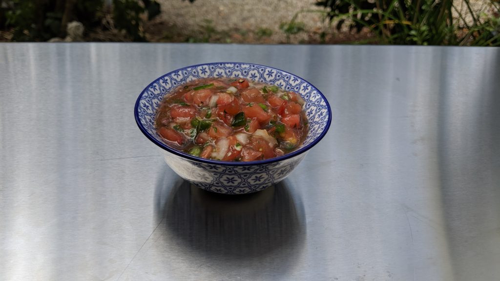 Purple Cherokee Salsa in a blue and white bowl on a stainless steel countertop.