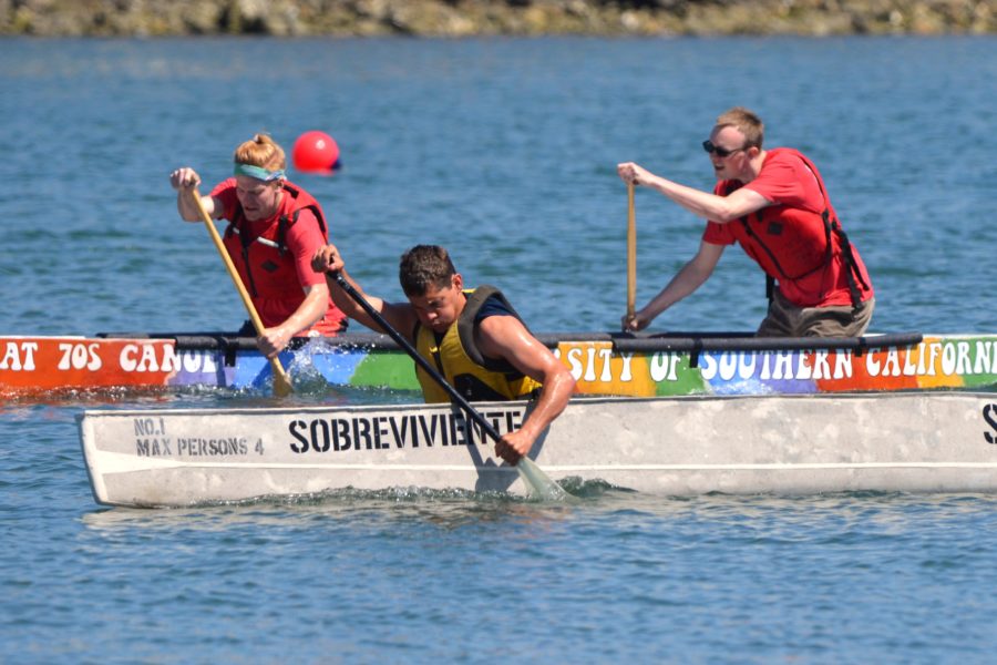 Two concrete canoes with three paddlers racing them in the water